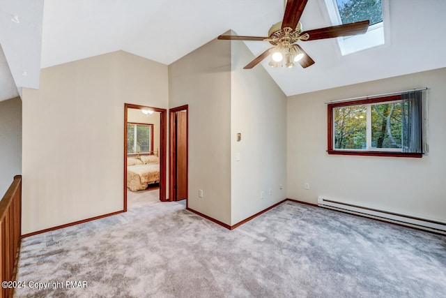 unfurnished bedroom featuring baseboards, carpet, vaulted ceiling with skylight, a ceiling fan, and a baseboard radiator