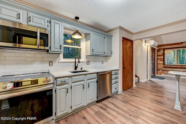 kitchen with light wood finished floors, a wall mounted air conditioner, light countertops, stainless steel appliances, and a sink