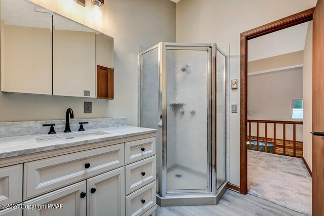 full bath with vanity, a shower stall, and wood finished floors