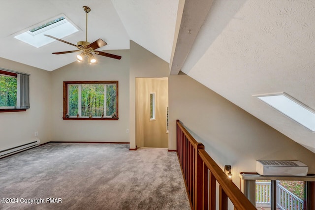 additional living space with carpet, baseboards, a baseboard radiator, ceiling fan, and lofted ceiling with skylight