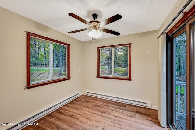 spare room with a textured ceiling, wood finished floors, and a baseboard radiator