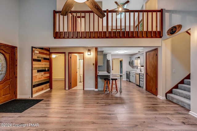 foyer with stairs, baseboards, wood finished floors, and a ceiling fan