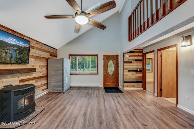 foyer entrance featuring wood finished floors, a ceiling fan, a baseboard radiator, a wood stove, and wood walls