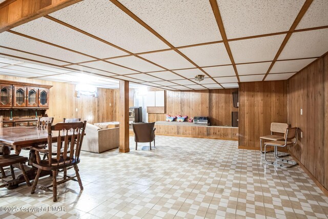 dining area featuring a drop ceiling and wooden walls