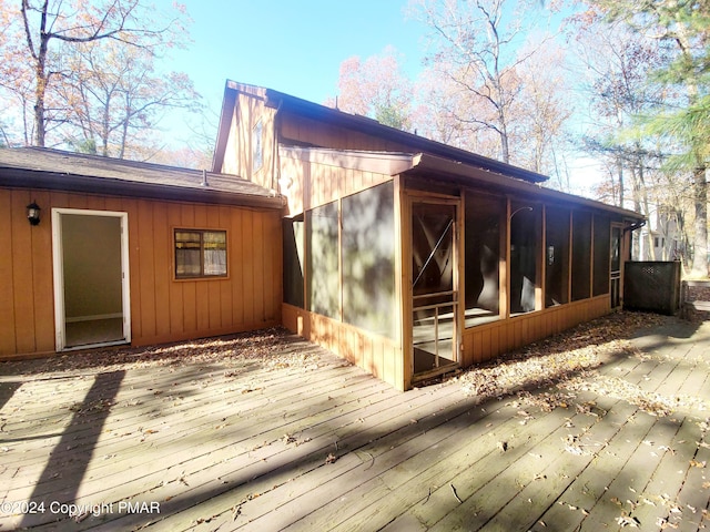 view of side of home with a wooden deck and a sunroom