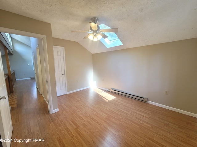 bonus room featuring a baseboard radiator, lofted ceiling with skylight, a ceiling fan, a textured ceiling, and light wood-type flooring