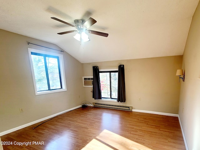 spare room with a baseboard radiator, lofted ceiling, a wall mounted AC, wood finished floors, and baseboards