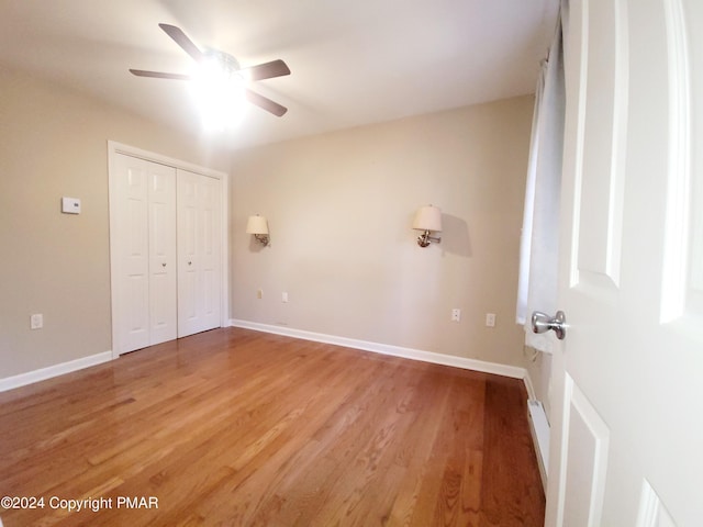 unfurnished bedroom featuring light wood-type flooring, a closet, ceiling fan, and baseboards