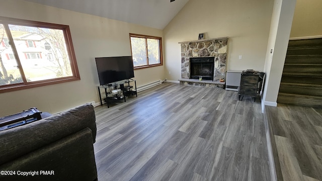 living area with wood finished floors, a stone fireplace, baseboards, and stairs