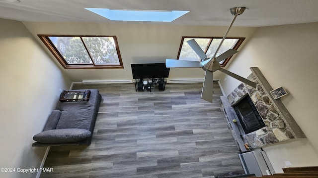 unfurnished living room with a skylight, baseboards, baseboard heating, and wood finished floors