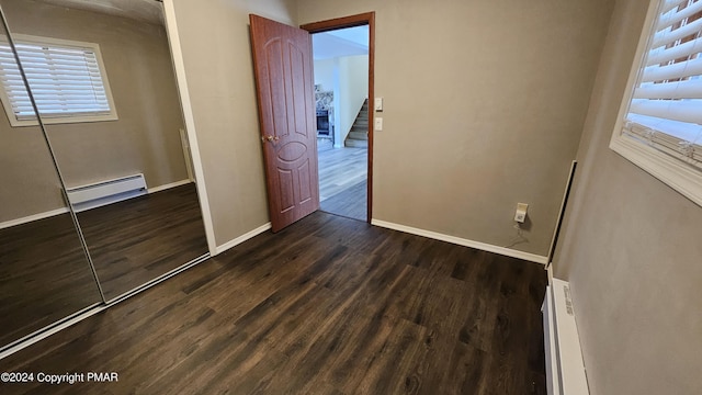 unfurnished bedroom featuring dark wood-style floors, a baseboard radiator, and baseboards