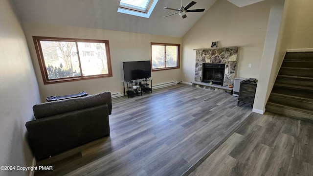 living room featuring high vaulted ceiling, a stone fireplace, dark wood-style flooring, a skylight, and stairs