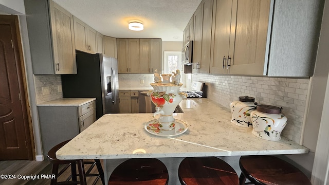 kitchen with a peninsula, a breakfast bar area, stainless steel appliances, and backsplash