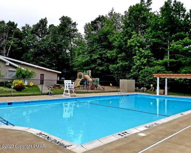 community pool featuring playground community and fence