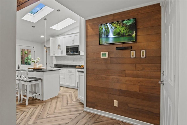 262 Marilou Ln, Bartonsville, PA 18321 - kitchen with stainless steel microwave, a skylight, dark countertops, tasteful backsplash, and white cabinets