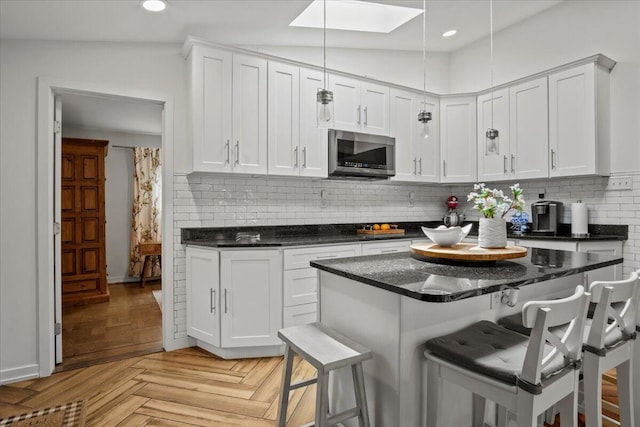 262 Marilou Ln, Bartonsville, PA 18321 - kitchen with stainless steel microwave, a kitchen bar, white cabinets, tasteful backsplash, and a skylight