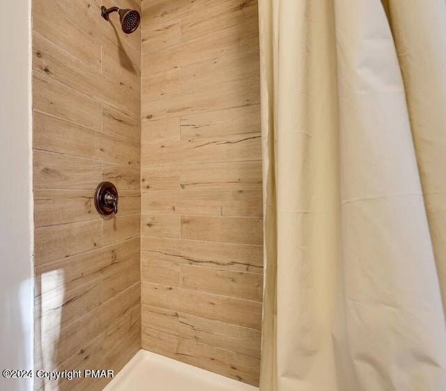 full bathroom with wooden walls and tiled shower