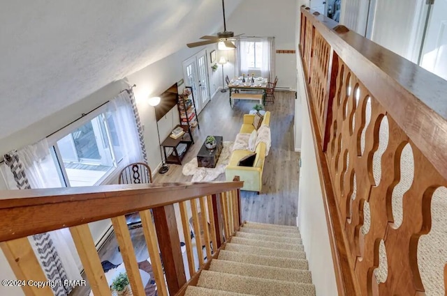 staircase featuring a ceiling fan, vaulted ceiling, and wood finished floors