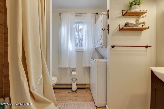 bathroom featuring stacked washer / drying machine, vanity, toilet, and wood finished floors