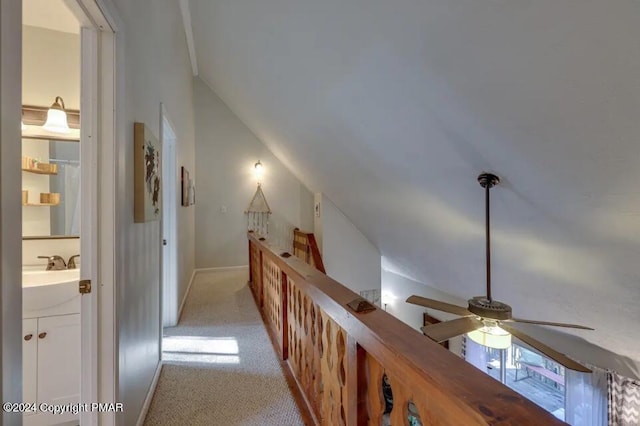 hallway with light carpet, a sink, and lofted ceiling