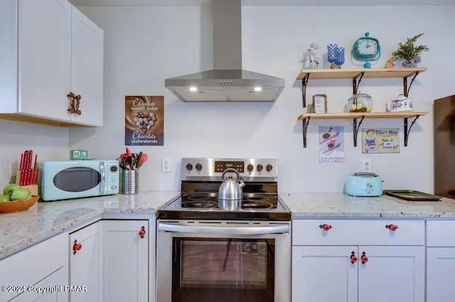 kitchen with white microwave, white cabinetry, wall chimney range hood, stainless steel electric range, and light stone countertops