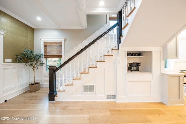 stairway featuring ornamental molding, visible vents, a decorative wall, and wood finished floors