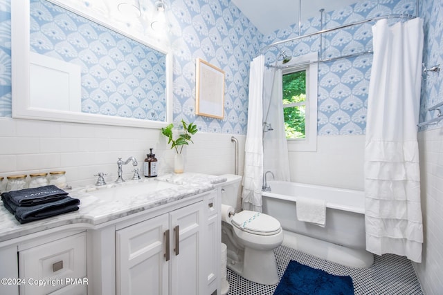 full bathroom featuring toilet, tile walls, wainscoting, shower / tub combo with curtain, and wallpapered walls