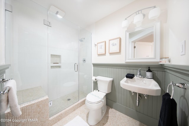 full bathroom with toilet, a wainscoted wall, a sink, tile patterned floors, and a stall shower