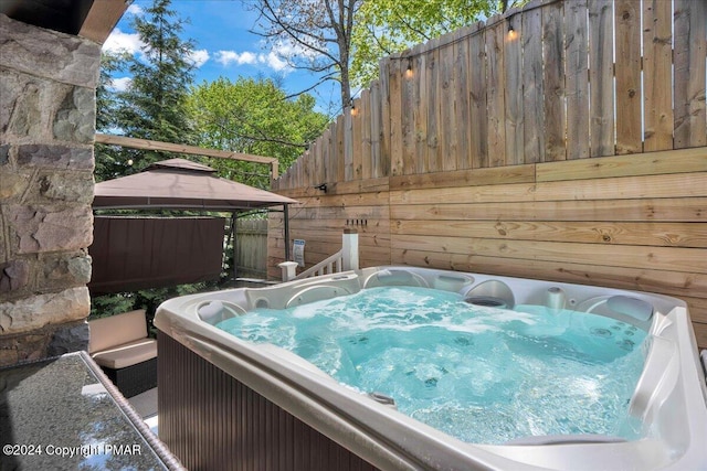 exterior space with an outdoor hot tub and a gazebo