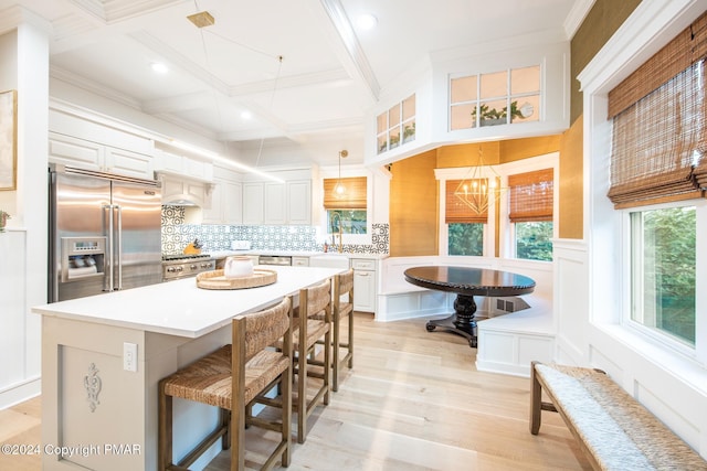 kitchen with appliances with stainless steel finishes, beam ceiling, coffered ceiling, and a healthy amount of sunlight