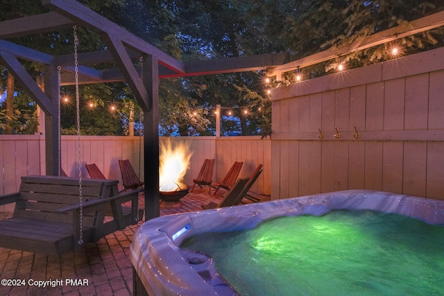 view of patio featuring an outdoor fire pit, a fenced backyard, and a hot tub