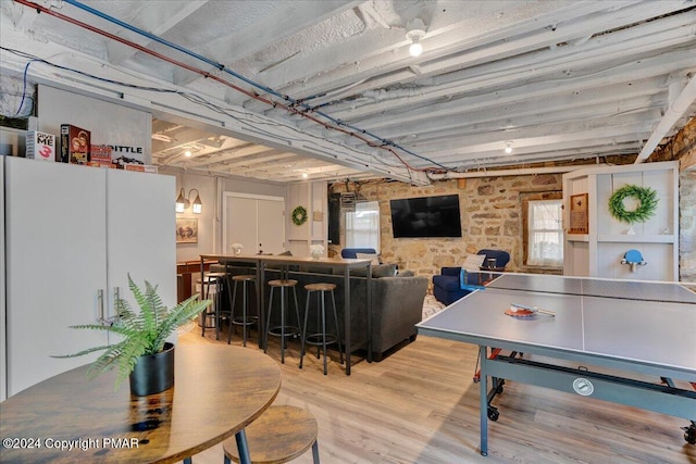 playroom with a dry bar, a wealth of natural light, and wood finished floors