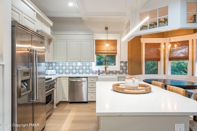 kitchen featuring premium appliances, a center island, crown molding, tasteful backsplash, and white cabinets