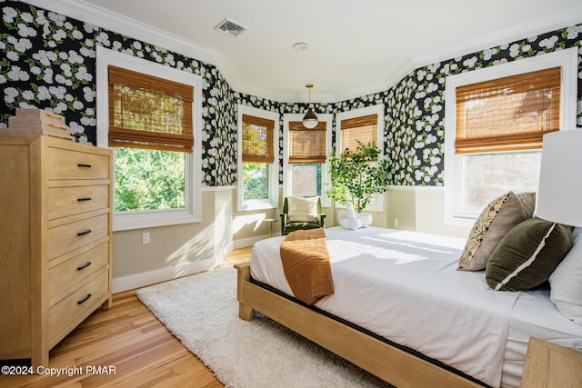 bedroom featuring light wood-style floors, baseboards, visible vents, and crown molding