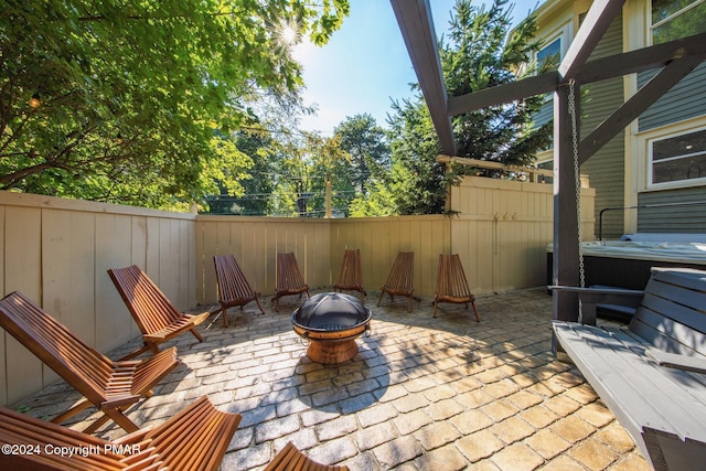 view of patio / terrace featuring a fire pit, a hot tub, and fence