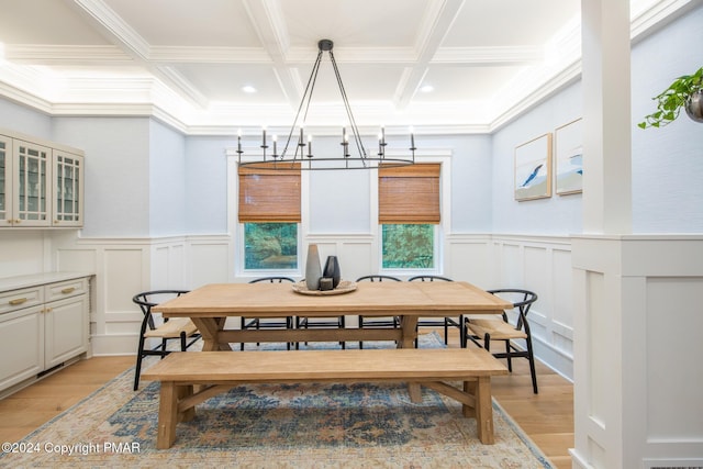 dining room with light wood-type flooring, a notable chandelier, coffered ceiling, and beam ceiling