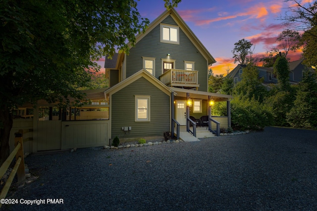 back of house at dusk with covered porch and a balcony