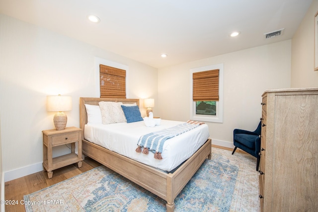 bedroom with baseboards, wood finished floors, visible vents, and recessed lighting