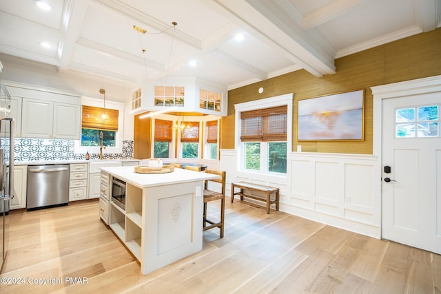 kitchen featuring a kitchen breakfast bar, beamed ceiling, a center island, light countertops, and stainless steel appliances