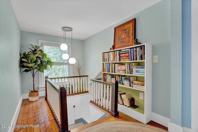 hall with light wood-type flooring, baseboards, and an upstairs landing