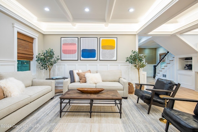 living area featuring stairs, ornamental molding, a decorative wall, and beam ceiling