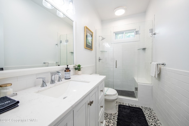 bathroom featuring toilet, vanity, tile walls, a shower stall, and tile patterned floors