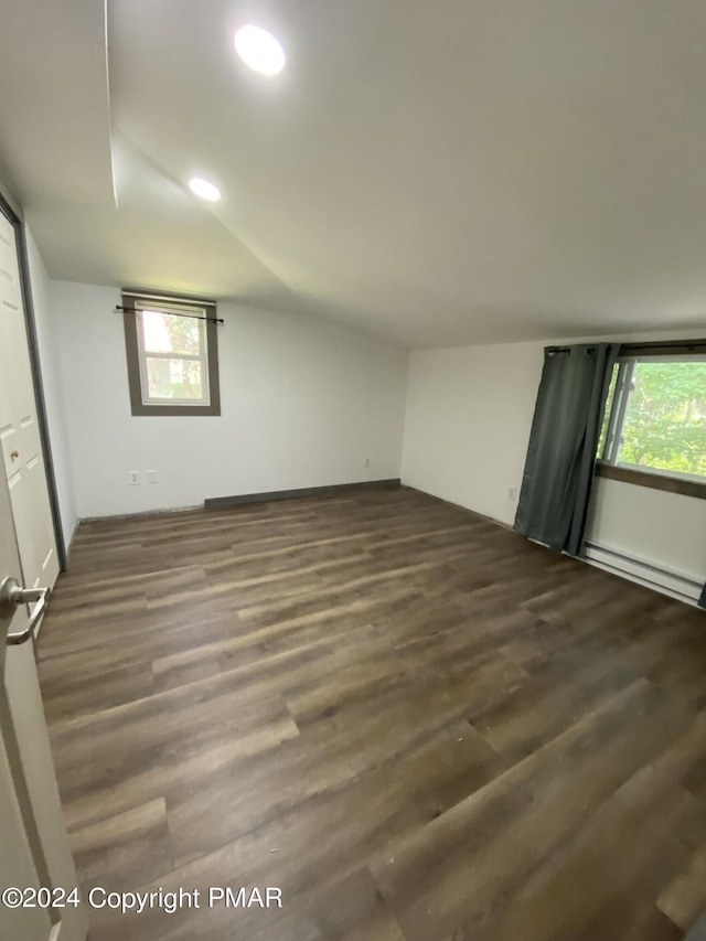 bonus room featuring dark wood-type flooring, a baseboard radiator, a healthy amount of sunlight, and lofted ceiling