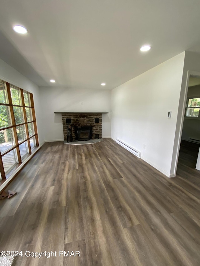 unfurnished living room featuring dark wood-type flooring, baseboard heating, a fireplace, and recessed lighting