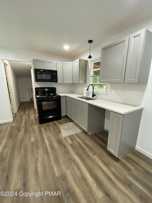 kitchen with dark wood-style flooring, light countertops, gray cabinetry, a sink, and black appliances