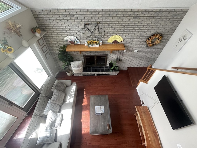5144 Hounds Ear Rd, Tobyhanna, PA 18466 - unfurnished living room featuring brick wall, a healthy amount of sunlight, wood finished floors, and a fireplace