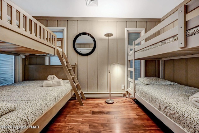 bedroom with visible vents, baseboard heating, and wood finished floors