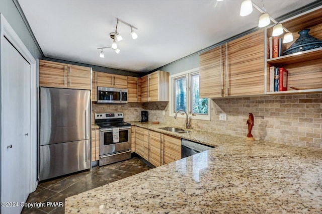 kitchen with light stone countertops, appliances with stainless steel finishes, decorative backsplash, and a sink