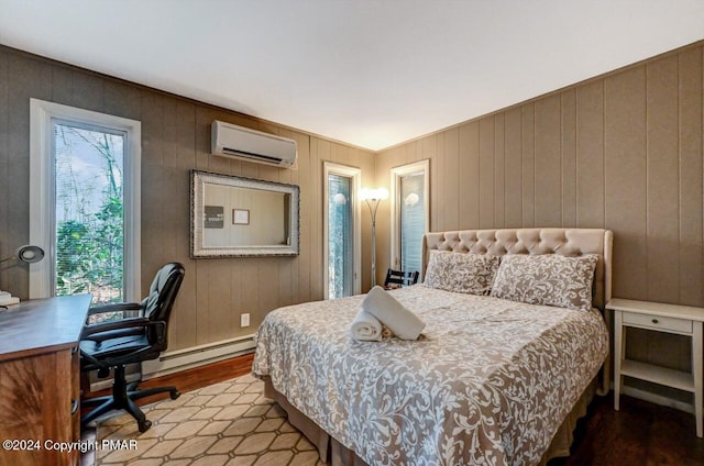 bedroom featuring a wall unit AC, a baseboard heating unit, and wood finished floors