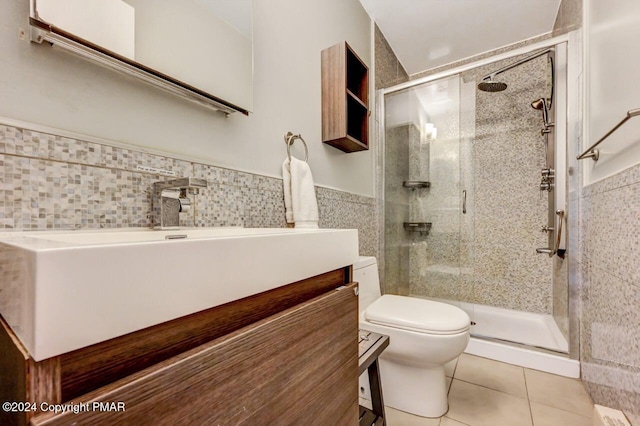 bathroom with tile patterned flooring, toilet, vanity, tile walls, and a stall shower